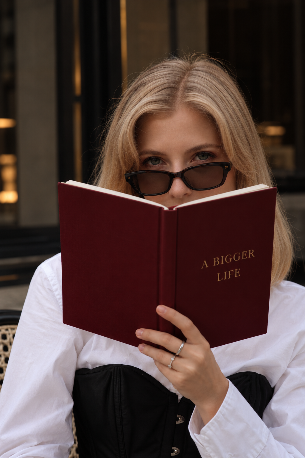 Julia peering over a burgundy book titled A Bigger Life